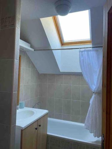 une salle de bain avec une baignoire, un lavabo et une fenêtre dans l'établissement Duplex T3, ski aux pieds, plein sud, Piscine, à Valloire