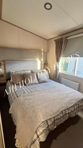 ein Schlafzimmer mit großem Bett und Fenster in der Unterkunft AJH Holiday Homes, Ty Mawr- Parkdeans Resort in Kinmel Bay