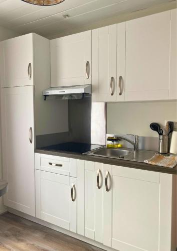 une cuisine avec des armoires blanches et un comptoir noir dans l'établissement Studio moderne et tout équipé au cœur de Bourbourg - gare à proximité, à Bourbourg