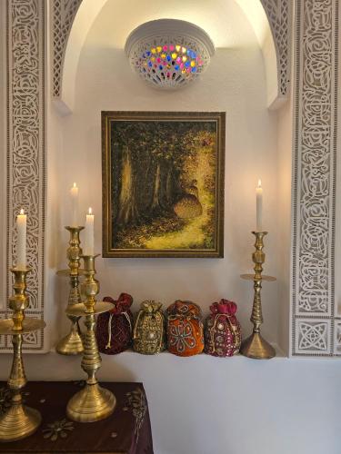 a table with candles and a painting on a wall at Riad Jnane d'Ô in Marrakech