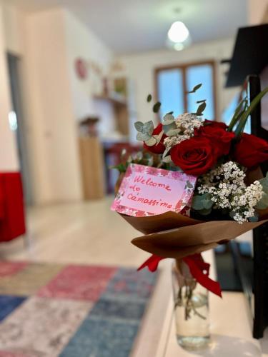 a vase with a bouquet of red roses and a note at Ca' Massima, il cuore a Monza in Lissone