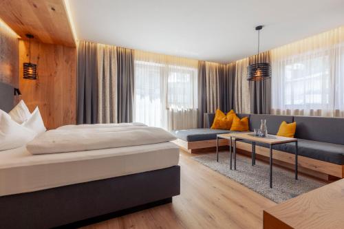 a hotel room with two beds and a couch at Hotel Mondin in Ischgl