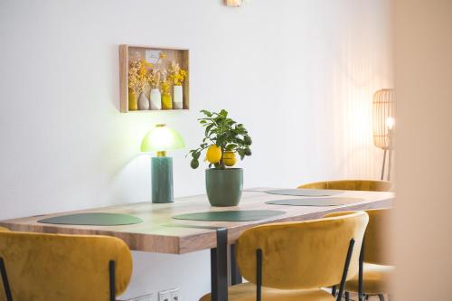a dining room table with a potted plant on it at Lemon3 - SAP Arena & Maimarkt - Smart-TV - Self-Checkin - Free Parking in Mannheim