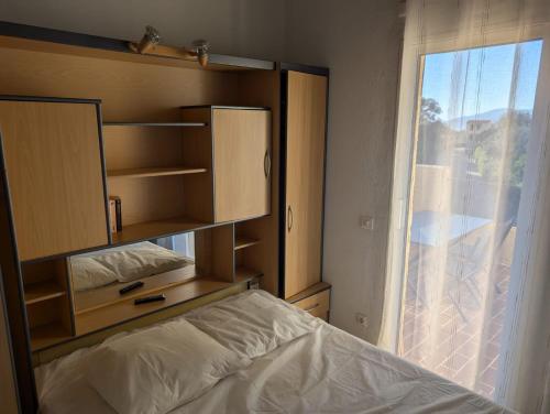 une chambre avec un lit et une grande fenêtre dans l'établissement Appartement accès piscine collective Porticcio Corse du sud, à Porticcio