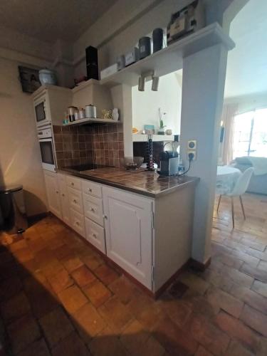 une cuisine avec des armoires blanches et un comptoir dans l'établissement Petite maison de pecheur, à Grimaud