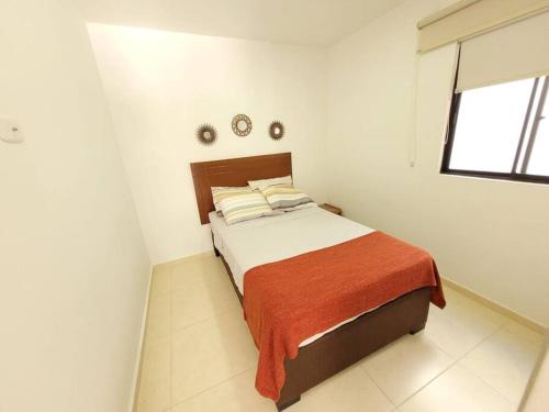 a white bedroom with a bed with a orange blanket at F111- Apartamento cerca al Club Campestre con piscina in La Tebaida