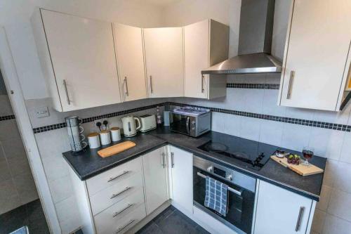 a kitchen with white cabinets and a stove top oven at Spacious 4 Bedroom House in Stoke on Trent in Stoke on Trent