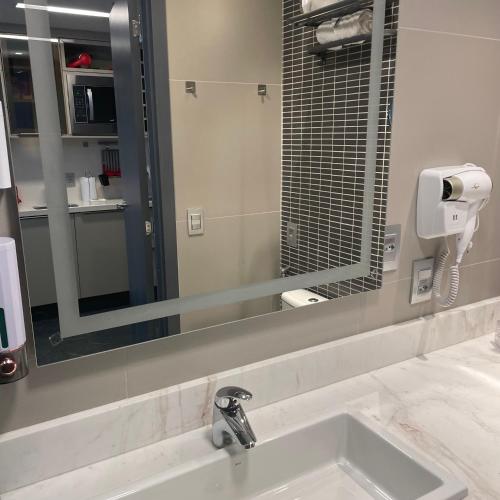 a bathroom with a sink and a large mirror at THE ONE - Flat Batel Premium in Curitiba