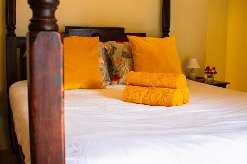 a bed with yellow pillows and a wooden head board at Landhuis Francia in Willemstad