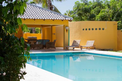 a swimming pool with two chairs and a house at Landhuis Francia in Willemstad