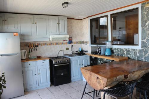 a kitchen with white cabinets and a table and a refrigerator at Delfín Apart in Pichilemu