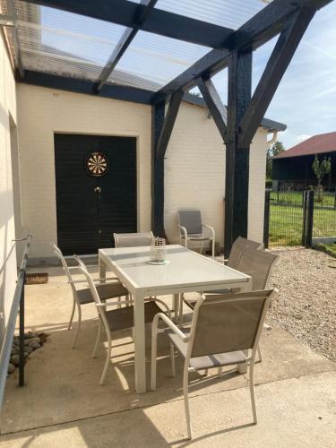 une table blanche et des chaises sur une terrasse dans l'établissement Au fil des champs, à Soyécourt