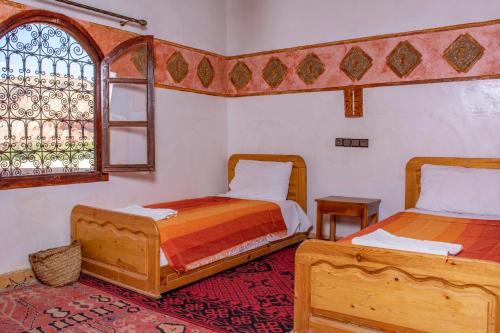 a bedroom with two beds and a window at Hotel Awayou in Bou Tharar