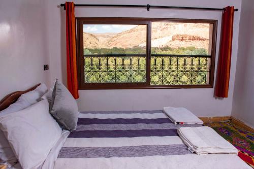 a bedroom with a bed and a window at Hotel Awayou in Bou Tharar