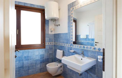 a blue tiled bathroom with a sink and a mirror at Vignola Baia Dei Mirti M3 in Vignola Mare