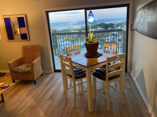 a dining room with a table and chairs and a large window at Jimmy's Beach Condo in Emerald Isle