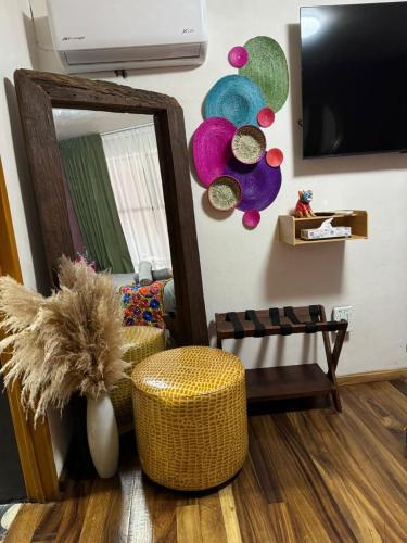 a living room with a mirror and a ottoman at Homestal California Hostal en Tlaquepaque in Guadalajara