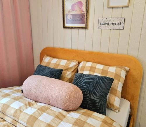 a bed with a pink pillow sitting on top of it at Idyllisk Mini-Hus i det charmerende Latinerkvarter in Viborg