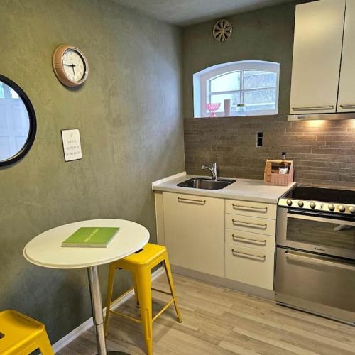 a kitchen with a table and a sink and a clock at Idyllisk Mini-Hus i det charmerende Latinerkvarter in Viborg