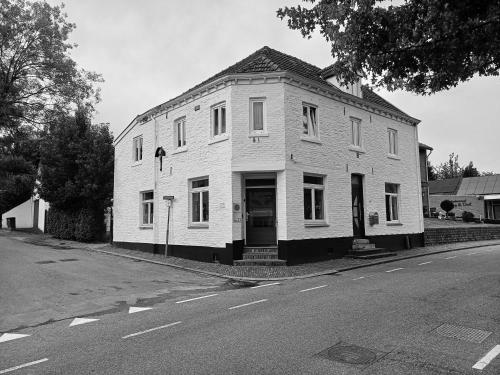 an old white house on the side of a street at Anno 1877 appartement met tuin in Slenaken