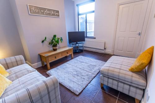a living room with two couches and a tv at Spacious 4 Bedroom House in Stoke on Trent in Stoke on Trent