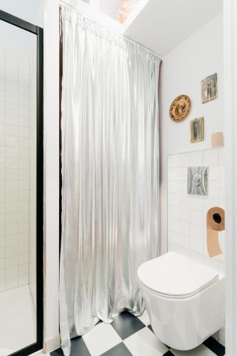 La salle de bains est pourvue d'un rideau de douche blanc et de toilettes. dans l'établissement Chez Lucie COZY RBNB, à Strasbourg