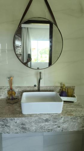 a bathroom with a white sink and a mirror at Barra de Jacuípe - Condomínio Parque Jacuípe -Mansão Caldeira in Camaçari