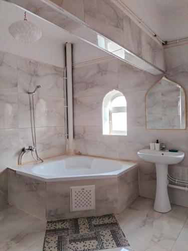 a white bathroom with a tub and a sink at Maison RKA in Bejaïa