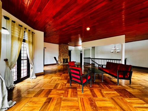 a dining room with a table and red chairs at Greenmoret AgriTourism Villa in Bandarawela