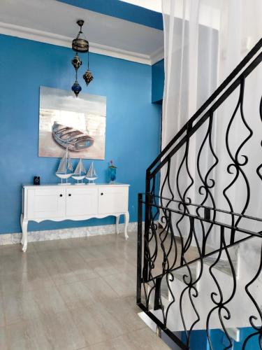 a blue room with a staircase and a white dresser at Maison RKA in Bejaïa