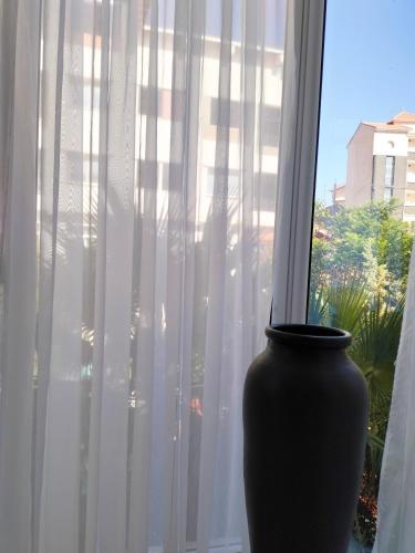 a black vase sitting in a window with curtains at Maison RKA in Bejaïa