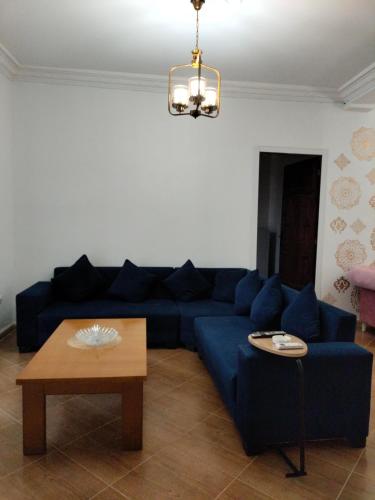 a living room with a blue couch and a table at Maison RKA in Bejaïa