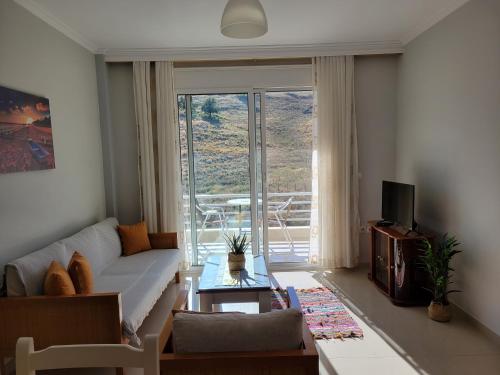 a living room with a couch and a large window at Llamani Apartments in Himare