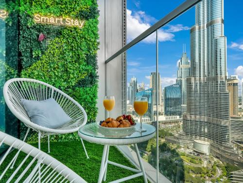a balcony with a table and two glasses of orange juice at SmartStay at Grande Signature - Burj Khalifa View - 5 min Dubai Mall - Downtown Dubai - Brand New Luxury Apartments in Dubai