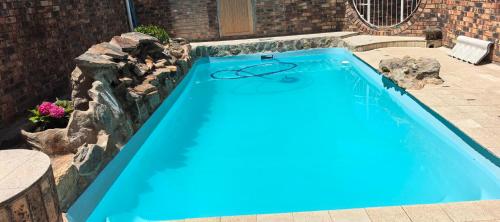 a blue swimming pool with a rock wall at Calming Waters Guesthouse in Grahamstown