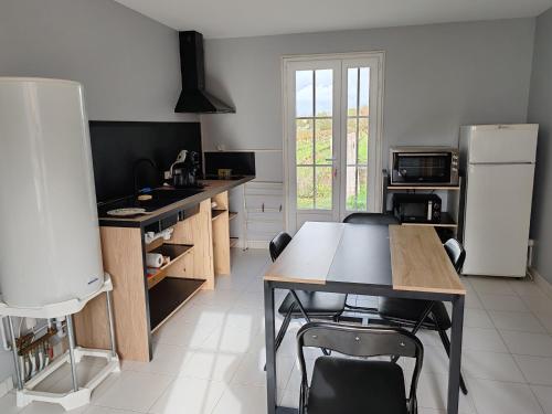 a kitchen with a table and a refrigerator at Le Clos de Vrillant in Anglade