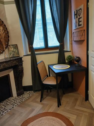 a table and chair in a room with a window at Les Loges Du Théatre 160m2 PRIVÉ 14 personnes MAX tout équipé a 200m de l'AVENUE DE CHAMPAGNE et toutes commodités DEGUSTATION CHAMPAGNE OFFERTE jacuzzi sauna jeux velos EMPLACEMENT EXCEPTIONNEL et CHIC in Épernay