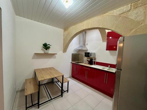une cuisine avec des placards rouges et une table en bois dans l'établissement studio sommieres, à Sommières