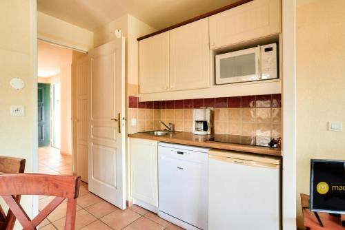 a kitchen with white cabinets and a microwave at Résidence Le Parc d'Arradoy - maeva Home - Appartement 2 pièces 5 personnes - Sélection MAE-2374 in Uhart-Cize