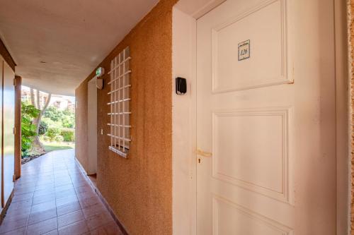 un couloir avec une porte blanche et du carrelage. dans l'établissement Résidence le Village de Cap Esterel - maeva Home - Appartement 2 pièces 5 personnes - Confort MAE-2631, à Saint-Raphaël
