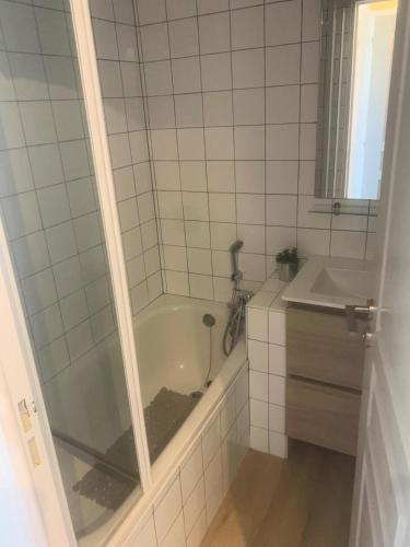 La salle de bains est pourvue de carrelage blanc, d'une baignoire et d'un lavabo. dans l'établissement Les Appartements aux Restanques du Golfe de St Tropez - maeva Home - Appartement climatisé 2 pièces 4 personnes, vue mer, facile d'accès - Sélection MAE-9371, à Grimaud