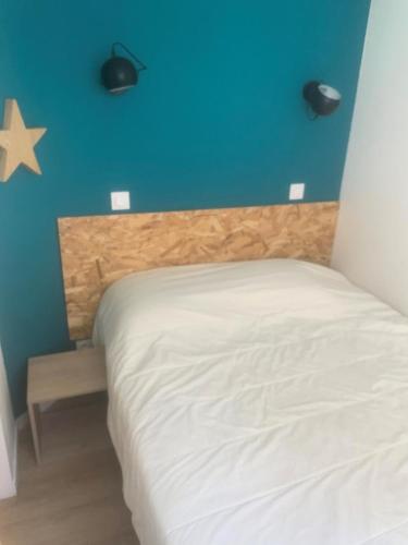 une chambre avec un lit blanc avec un mur bleu dans l'établissement Les Appartements aux Restanques du Golfe de St Tropez - maeva Home - Appartement climatisé 2 pièces 4 personnes, vue mer, facile d'accès - Sélection MAE-9371, à Grimaud