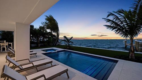 a swimming pool with chairs and a view of the ocean at Oceanfront Oasis by Last Key Realty in Key West