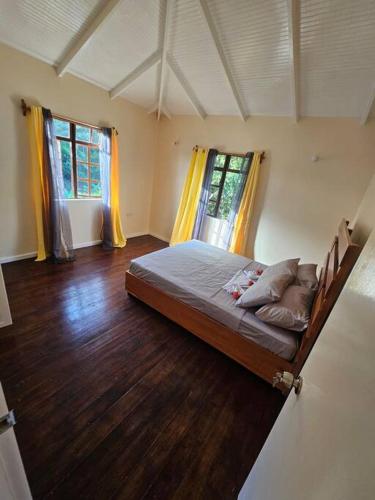 a bedroom with a bed in a room with wood floors at Jardin Damon in Soufrière