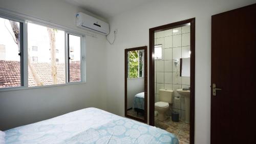a bedroom with a bed and a bathroom with a mirror at Residencial Adolfo - Mestre Naro in Bombinhas