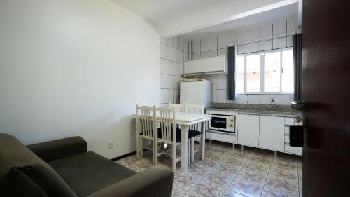 a kitchen with a couch and a table in a room at Residencial Adolfo - Mestre Naro in Bombinhas