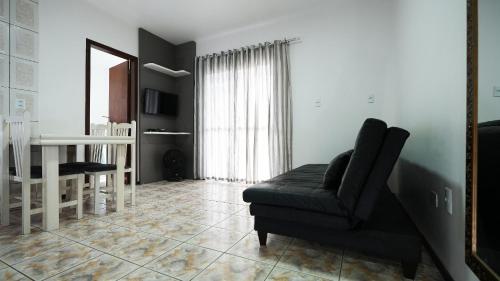 a living room with a black chair and a table at Residencial Adolfo - Mestre Naro in Bombinhas