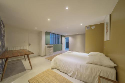 Un dormitorio con una gran cama blanca y una mesa. en Villa Panouse, en Marsella