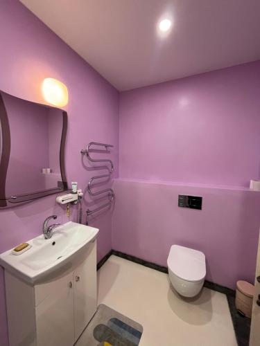 a purple bathroom with a toilet and a sink at Comfortable Townhouse in Vilnius