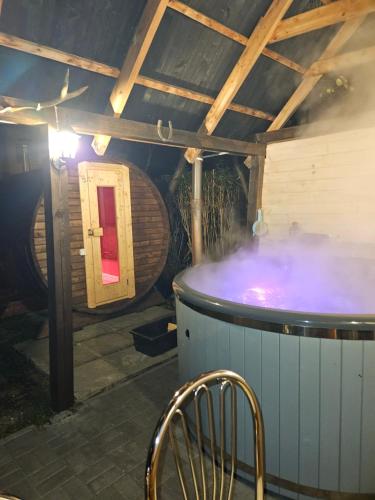 a hot tub in a room with a chair and a barrel at Domek Domino in Korbielów